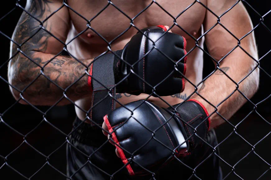 MMA fighter wearing black MMA gloves inside a cage, symbolizing intensity and professional mixed martial arts training
